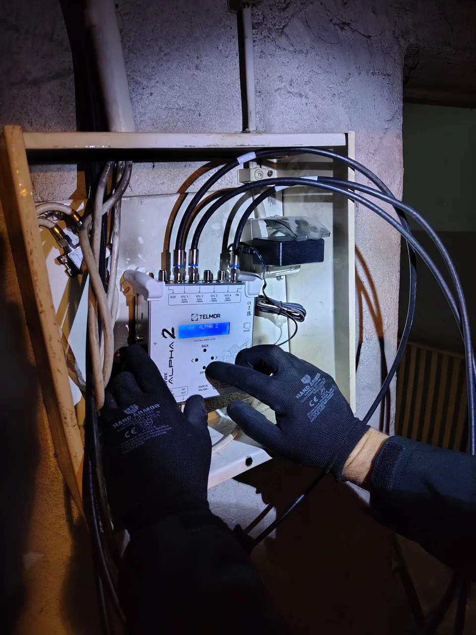 Praca instalatora przy wzmacniaczu kanałowym i przewodach instalacji zbiorczej